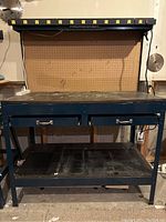 Front view of Master Craft workbench with pegboard back and overhead power strip showing drawers and lower shelf.