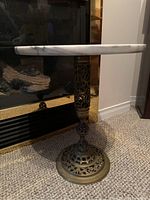 Side view of pedestal table showing gold ornate base and marble top installed.