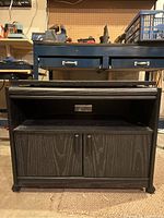 Front view of wood TV stand with swivel top, showing two closed front doors and open shelf above.