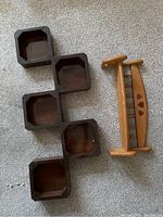 Light wood shelf with curved handles and three heart and leaf inlays, alongside the disassembled dark brown cubby shelf displayed on carpet.