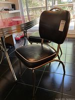 Side and front angled view of a single chrome and black vinyl 1950s diner chair