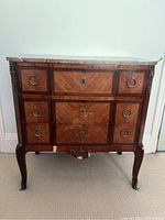 Front view of antique chest of drawers showing marble top, wood veneer drawers with brass ring pulls and ormolu mounts.