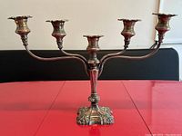Full view of antique silver plated candelabra showing five arms holding candle cups, ornate base, and plated surface.