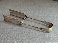 Full view of sterling silver asparagus tongs showing the slotted ends and hinge mechanism.