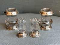 Photo showing entire set of two sterling silver and glass candle holders and matching pair of salt and pepper shakers on fabric surface.