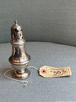 Full view of the antique English sterling silver sugar shaker with auction tag.
