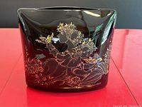 Front view of black porcelain pillow vase with detailed gold line art of figures and flowers.