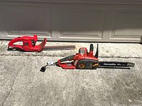 Both power tools shown side by side on concrete ground: red Spectra Tools hedge trimmer with blade cover and red/black Homelite 14 inch electric chainsaw.