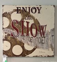 Front view of square canvas wall art with 'Enjoy the Show' text and vintage film reel and ticket strip design in muted brown and beige tones.