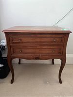 Front view of a vintage walnut Queen Anne style end table showing two drawers with round metal knobs and elegant cabriole legs.