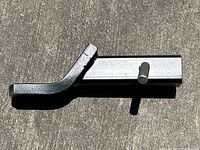 Photo of first black metal ball mount trailer hitch with locking pin, showing side profile and curved ball coupling end.