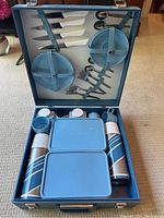 Photo showing vintage Braxton blue travel picnic set opened in the original hard case with all utensils, plates, cups, thermoses and containers neatly organized.