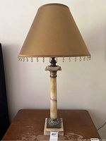 Full view of the marble column table lamp on a wooden surface, showing the overall form with shade off.