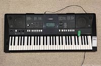 Full top view of Yamaha PSR E423 keyboard showing keys, display, control buttons, and integrated speakers.