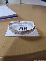 Single silver cuff bracelet with detailed floral and ornamental design pattern.