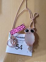 Photo of a jeweled owl pendant necklace with a long rose gold-tone chain laid flat with auction tag visible.