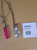 Photo of teardrop pendant necklace on wooden surface showing chain and MaxSold lot card.