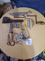 Overview photo showing all assorted wrenches and hand tools from above on a round wooden table.