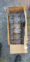 Overhead view of a cardboard box filled with smaller rock glasses organized in compartments.