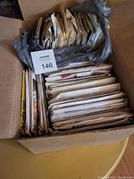 Box filled with numerous folded sewing patterns and envelopes.