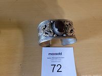 Front view of vintage silver-tone cuff bracelet with dark agate stone and intricate detailed patterns on the band.