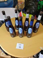 Seven Coors Lite bottles arranged on a wooden table, showing front labels and overall lot condition.
