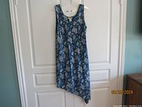 Full view of the blue printed sundress hanging on a white door, showing the dress pattern and cut.