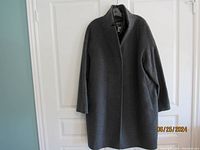 Dark gray wool and cashmere coat hanging on white door, front view