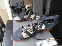 Side view of black textured leather Vince Camuto Roman style lace-up sandals showing finish, laces, and sole