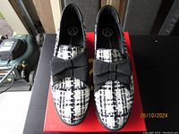 Front view of black and white platform shoes with fabric bow on each, showing pattern and platform height