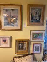 Photo showing all six framed art pieces mounted on a wall above a sofa with a cushion.