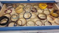 Box showing an assortment of bangle bracelets in various colors and a few beaded bracelets