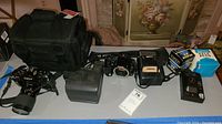 Full lot overview including cameras, camera bag, flash, lens multiplier and accessories arranged on table