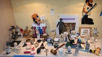 Wide view of lot showing multiple figurines, mugs, and the cast iron coin bank at front