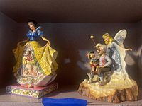 Two figurines displayed side by side: Snow White on left and Pinocchio & Geppetto with Blue Fairy on right