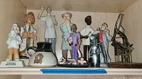 Shelf with multiple ceramic figurines including dental themed dentists and a ceramic mug.