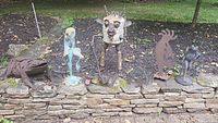 Overview of all six metal garden sculptures arranged on a stone ledge outdoors