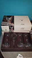 Three boxes of Cristal d'Arques Classic wine glasses with original packaging. Each box contains 4 wine glasses with visible classic vertical cut pattern on the bowl.