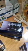 Three boxed sets of Mikasa Cheers wine glasses stacked on the floor, showing brand and packaging.