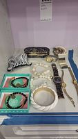 Full lot arranged on shelf showing watches, bracelets, jewelry box, and hair clip