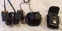 Three pairs of binoculars arranged in a row showing their size and cases.
