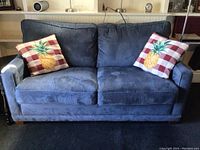 Front view of blue La-Z-Boy loveseat with 2 pineapple checkered pillows.