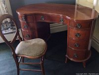 Front view of kidney-shaped desk paired with wooden chair