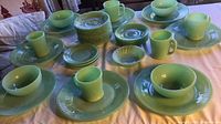 Full set of jade green dishes including plates, mugs, small plates, and finger bowl displayed on table