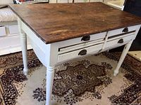 Full view of the kitchen island showing the wooden top, white painted base with four drawers and turned legs.