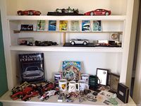 Overall shelf view showing diecast cars on upper shelves and assorted memorabilia below