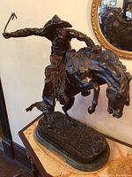 Front view of full statue showing cowboy and bucking horse, marble base and plaque