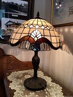 Front view of the stained glass lamp showing illuminated shade with multicolor accents and metal base.