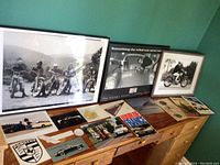 Full view of framed motorcycle and automotive prints displayed on dresser along with loose automotive brochures and magazines.
