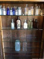 Full view of three glass shelves filled with assorted bottles